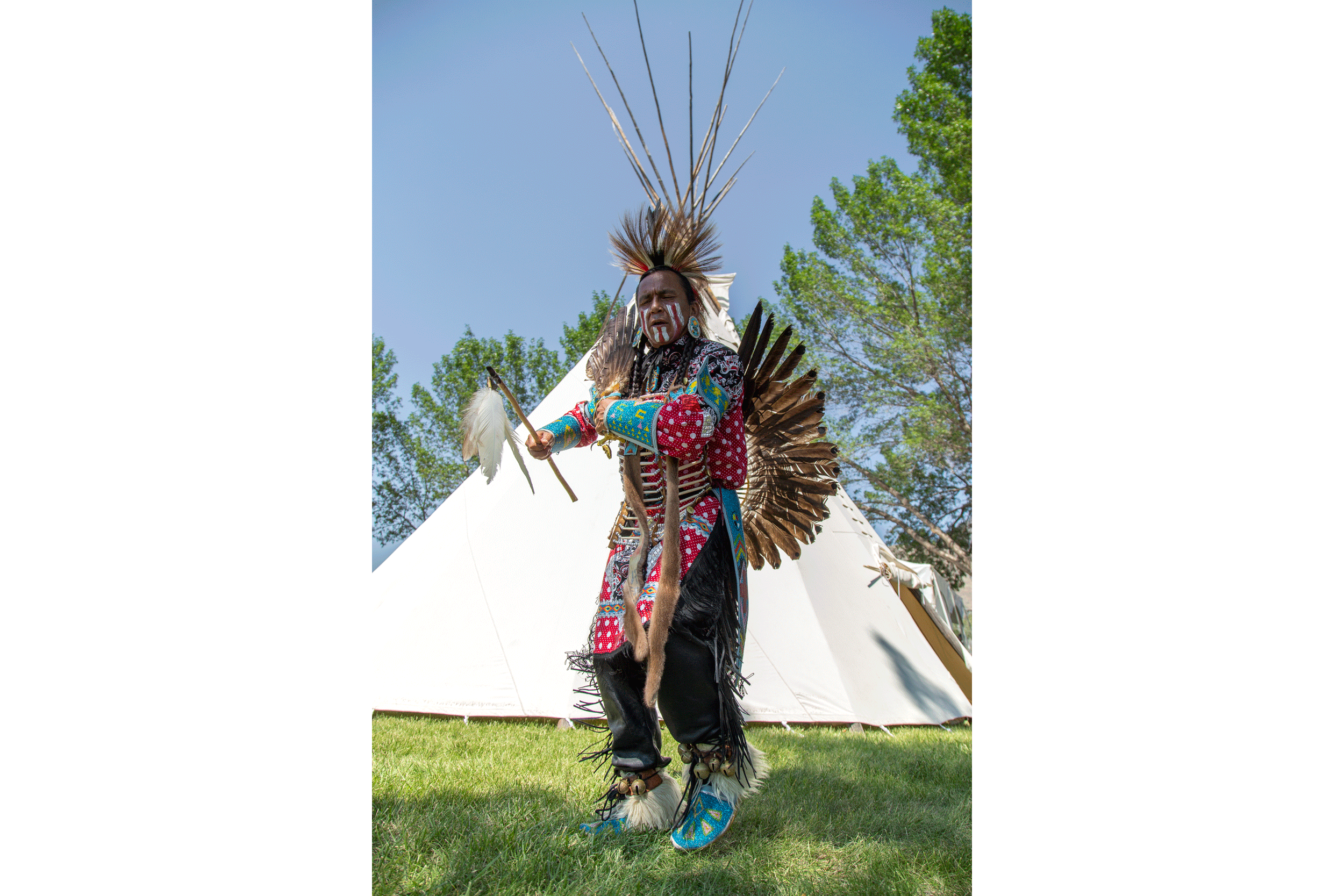 Indigener Mann aus Kanada tanzt vor einem Tipi.