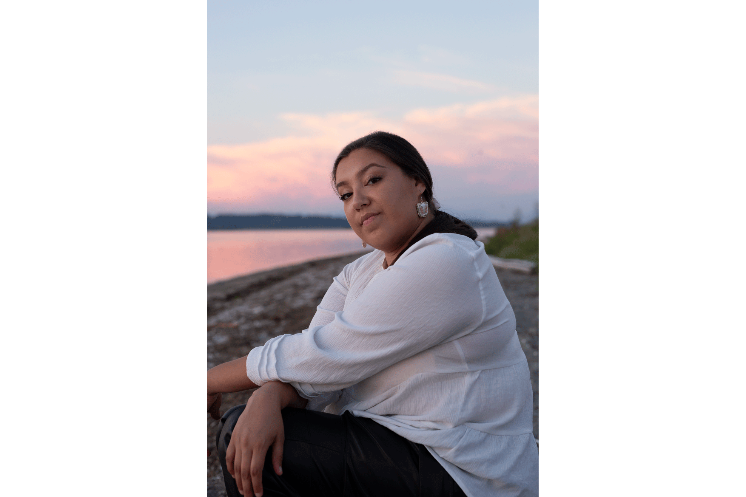 Indigene Frau sitzt bei Sonnenuntergang am Meer in Vancouver.